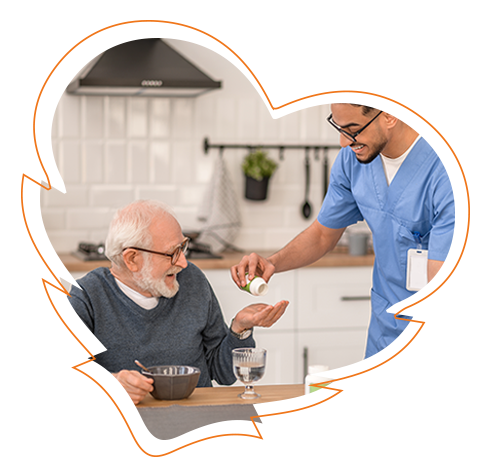 An elderly man receiving medication from a healthcare professional at a dining table.