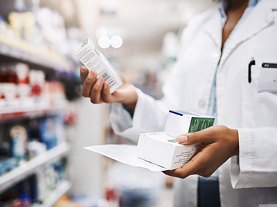 The image depicts a person standing behind a counter with various products, including boxes and bottles, possibly in a pharmacy setting.